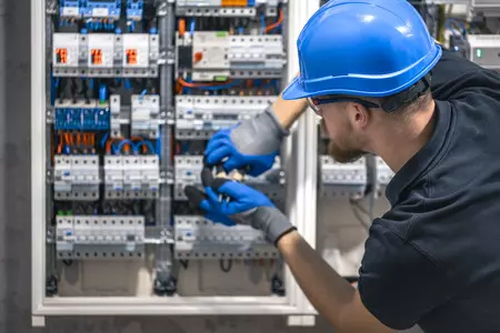 dogodki/male-electrician-works-switchboard-with-electrical-connecting-cable
